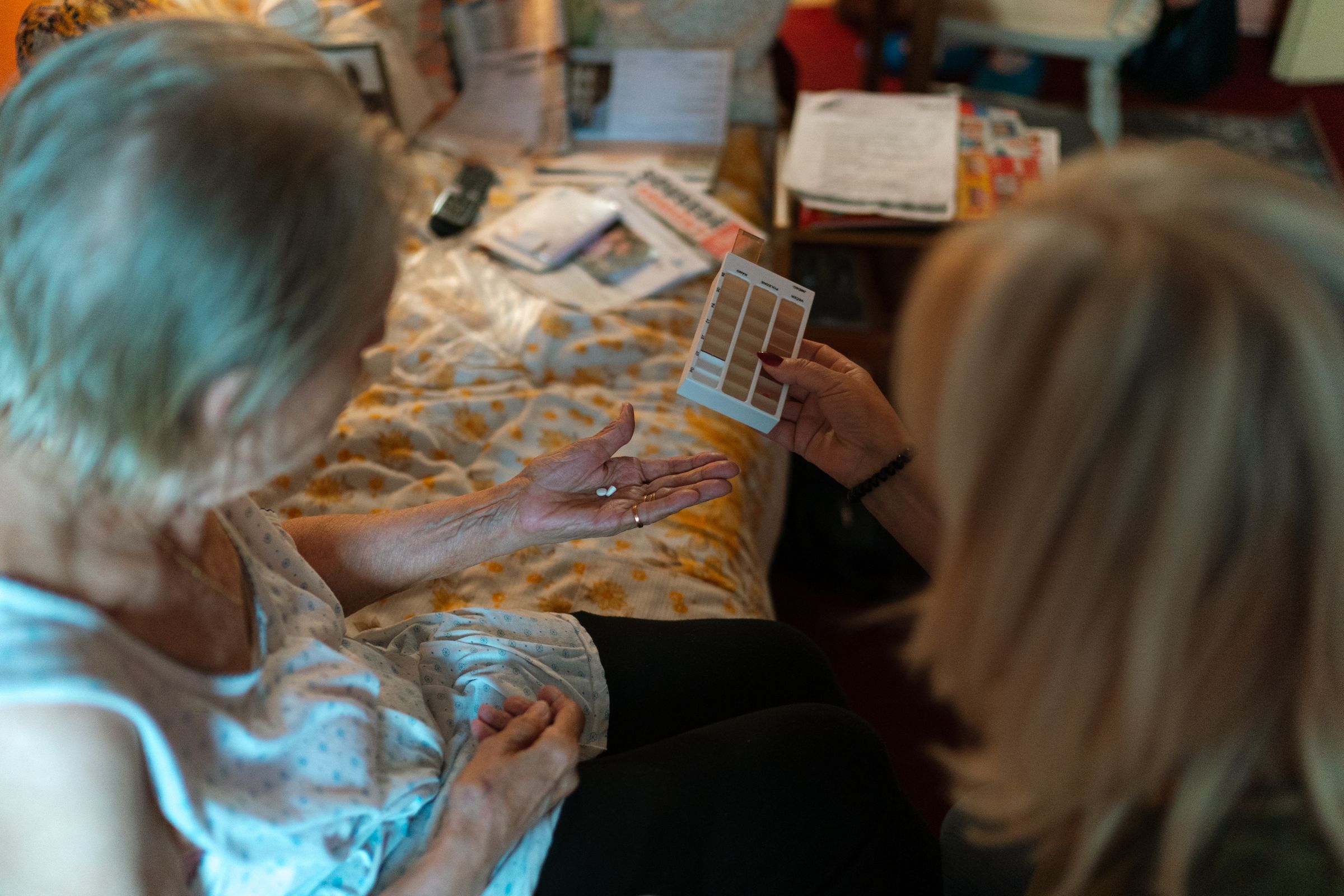 A caregiver helping an older woman understand her medication at home